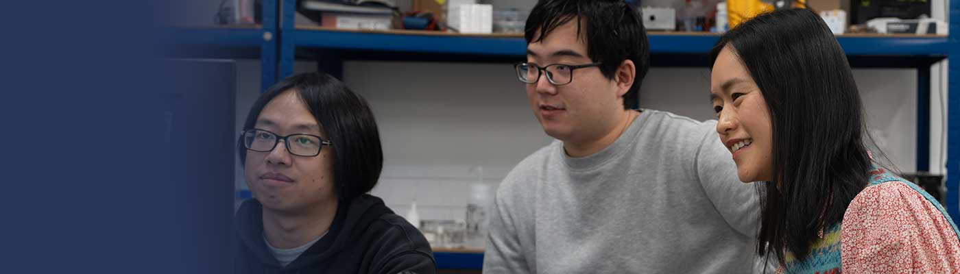 Qian yang and her colleagues looking at a computer screen.